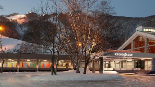 two trees in the snow in front of a building at The Green Leaf, Niseko Village in Niseko