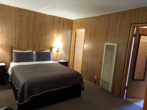 1 dormitorio con 1 cama grande y paredes de madera en Lakeview Motel, en Lake Isabella