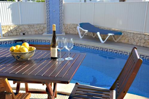 una mesa con botellas de vino y copas junto a una piscina en Villa Barros by GalanteVasques, en Carvoeiro