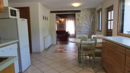 une cuisine avec une table et un réfrigérateur blanc dans l'établissement Gite des Goganes, à Denée