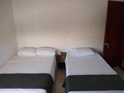 Habitación pequeña con 2 camas y paredes blancas. en Hotel Don Luis en Ocaña