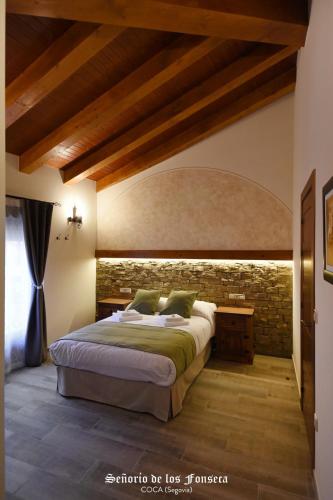 a bedroom with a bed and a brick wall at Señorío de los Fonseca in Coca