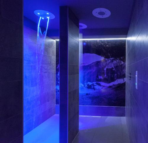 a dark bathroom with a shower with blue lights at Hotel Canin in Sella Nevea