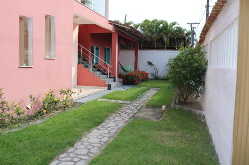 une passerelle à côté d'une maison rose avec une cour dans l'établissement Flat - Coroa Vermelha, à Santa Cruz Cabrália
