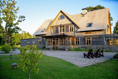 een groot houten huis met een gambrel dak bij Rezidence Kurzeme in Kāķīši