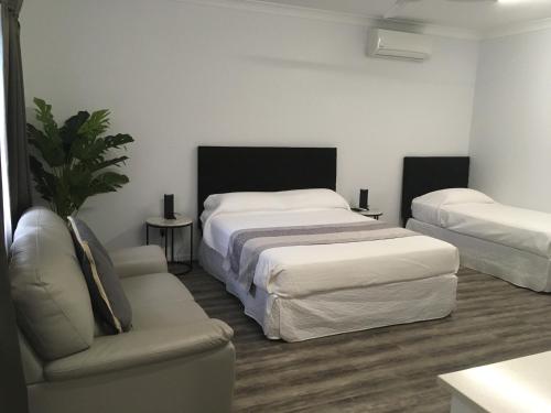 a bedroom with two beds and a chair and a couch at Escape On Lake in Cairns