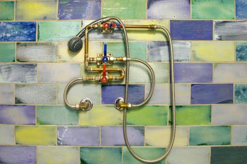 een douche met een slang aan een betegelde muur bij Apartment Center in Gmunden