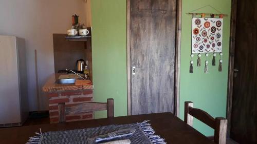a dining room with a table and a kitchen at Cabañas Las Acacias in San Clemente del Tuyú