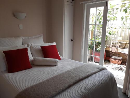 a white bed with two red pillows in a bedroom at Ranfurly Cottage in Raetihi