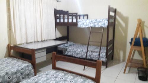 2 Etagenbetten in einem Zimmer mit einem Schreibtisch und einer Leiter in der Unterkunft Hostel Famille Brun Trevo in São João da Boa Vista