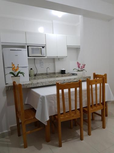 een keuken met een tafel met stoelen en een magnetron bij Apto House 06, Praia Grande Ubatuba in Ubatuba