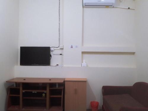 a living room with a table and a tv on a wall at Jakson Homestay in Batam Center