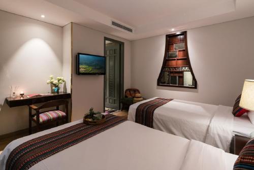 a hotel room with two beds and a desk at Au Lac Legend Hotel in Ho Chi Minh City