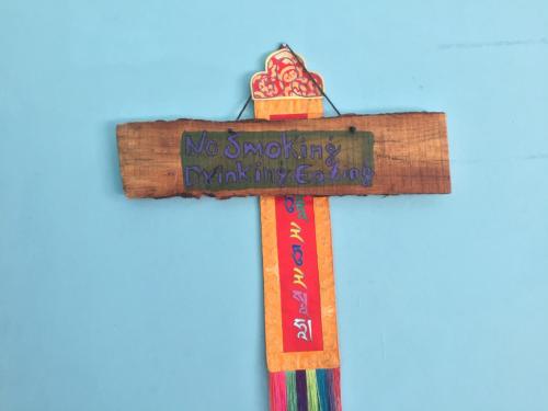 a wooden cross with a no smoking sign on it at Nepalaya Eco Hostel in Pokhara