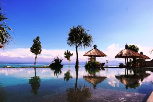 a pool of water with umbrellas and the ocean at Pemedal Beach Resort in Nusa Lembongan