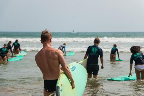 a group of people standing in the water with surfboards at Hangover Hostels Mirissa in Mirissa