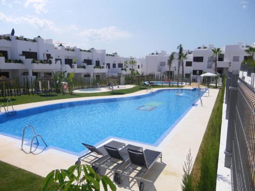 a large swimming pool with chairs and apartments at Kaki in San Juan de los Terreros