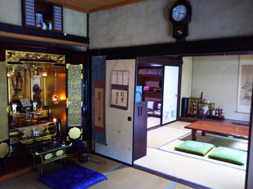 a room with a table and a clock on the wall at ゲストハウス『古民家の宿 梨 本 軒』 in Takai