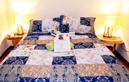 a bed with a quilt on it with two lamps at Guesthouse Casa Lapa in Alajuela City