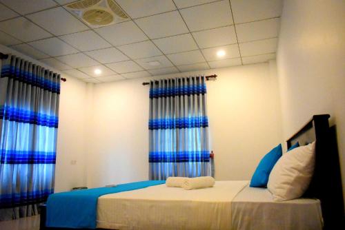 a bedroom with a bed with blue and white curtains at Lake Front Yala Safari in Kataragama