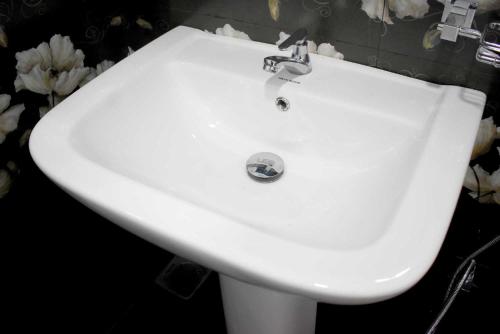 a white sink in a bathroom with flowers at Lake Front Yala Safari in Kataragama
