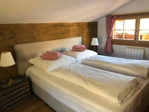 a bedroom with two beds with white sheets and red pillows at Chalet Tirolia in Kirchdorf in Tirol