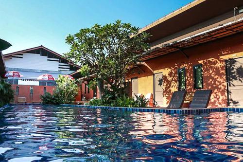 a swimming pool with two chairs next to a house at 2 Home in Chalong 
