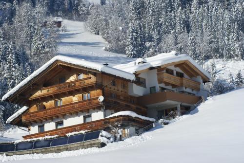 a building covered in snow with trees in the background at Ferienwohnung Bergheim in Fügenberg