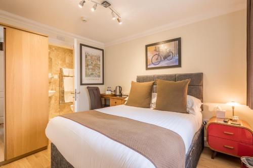 劍橋的住宿－秋季別墅酒店，一间卧室配有一张大床和红色的行李箱