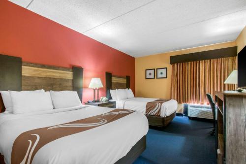 two beds in a hotel room with red walls at Quality Inn Carlisle PA in Carlisle