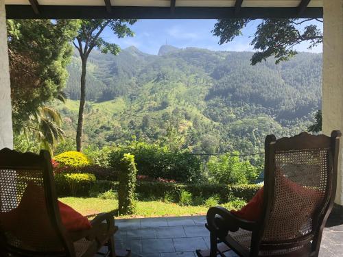 two chairs on a porch with a view of a mountain at Gammaduwa Heritage Bungalow and Tea Gardens in Matale