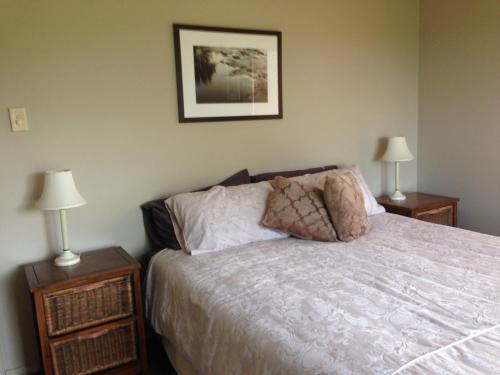 a bedroom with a white bed with two night stands at Toscana on Greenhills in Sutton Forest