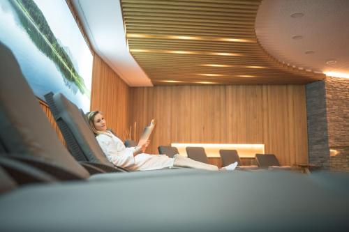 a woman sitting in a chair in a room at Das Salvator Iris Porsche Landhotel in Friesach