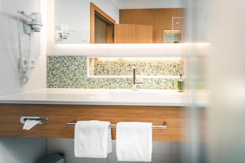 a bathroom with a sink and white towels at Das Salvator Iris Porsche Landhotel in Friesach