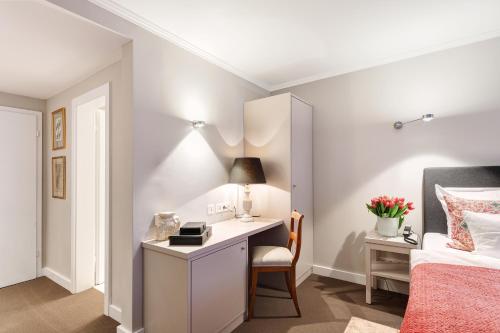 a bedroom with a desk next to a bed and a chair at Hotel Admiral in Munich