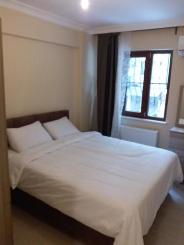 a bedroom with a large white bed with a window at Ataa Family Apartments in Bursa