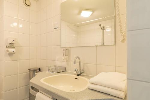 a white bathroom with a sink and a mirror at Fletcher Resort-Hotel Amelander Kaap in Hollum