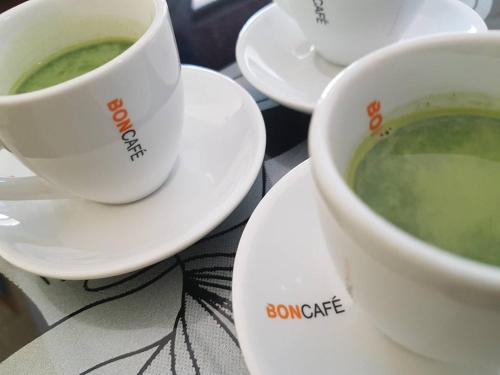 two cups of green soup on plates on a table at Amaretto Hostel in Surat Thani