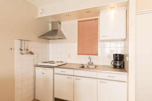 
a kitchen with white cabinets and white appliances at Fletcher Resort-Hotel Amelander Kaap in Hollum
