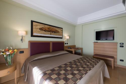 a hotel room with a bed and a flat screen tv at Artemis Hotel in Cefalù