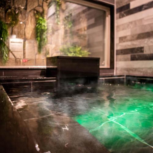 a bath tub filled with lots of green water at Super Hotel Nagano Iida Inter in Iida