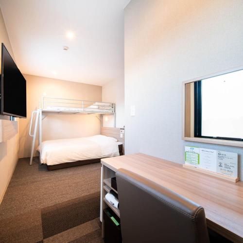 a hotel room with a bunk bed and a desk at Super Hotel Nagano Iida Inter in Iida