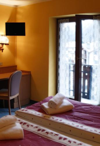 a bedroom with a bed with a window and a desk at Hotel Etoile De Neige in Valtournenche