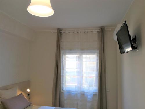 a bedroom with a bed and a window with a television at Michelangelo Home B&B in Rossano