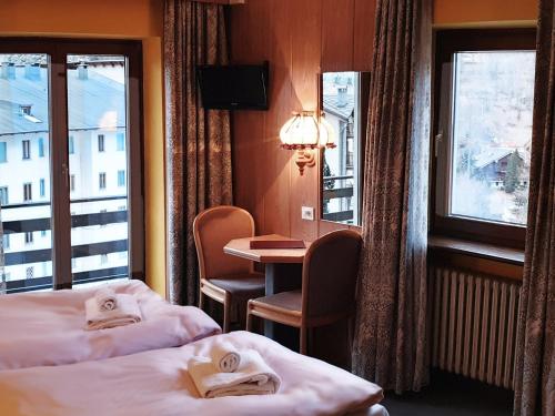 a hotel room with two beds and a table at Hotel Etoile De Neige in Valtournenche