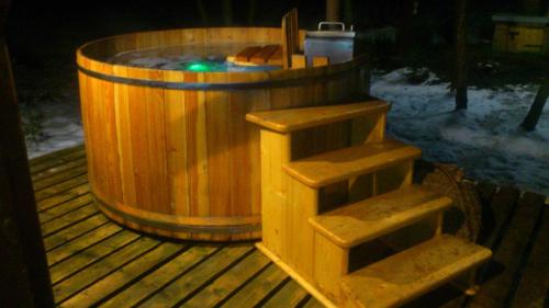 a wooden hot tub with steps in the snow at Chata pod pilskom in Sihelné