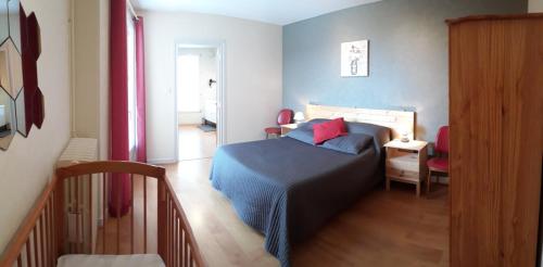 a bedroom with a bed with blue sheets and red pillows at Les Planchettes in Orcival