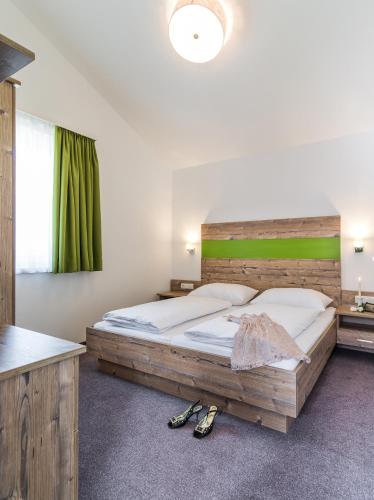 a bedroom with a large bed with a wooden headboard at Fuchs Apartments - inklusive Eintritt in die Alpentherme Gastein in Bad Hofgastein