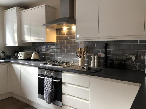 a kitchen with white cabinets and a stove at FREE Parking, Stylish and Spacious Bungalow in Bath