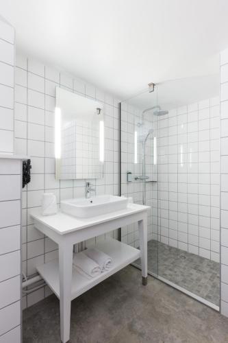 a white bathroom with a sink and a mirror at Dina Morgabine Saint Gilles in Saint-Gilles les Bains